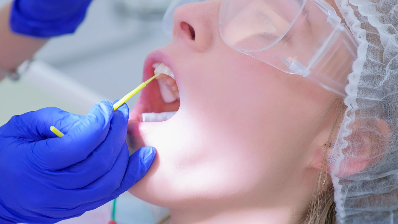 Dental professional applying fluoride treatment to a patient's teeth with an applicator