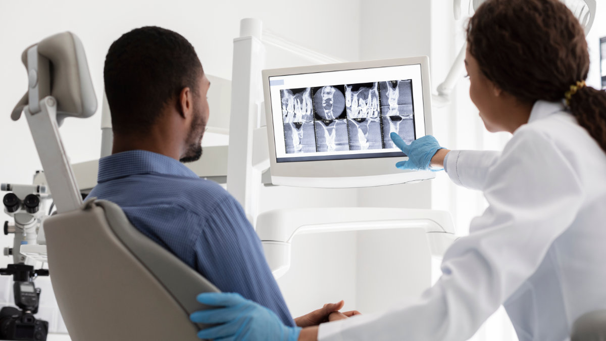 Dentist reviewing dental X-rays with a patient on a screen