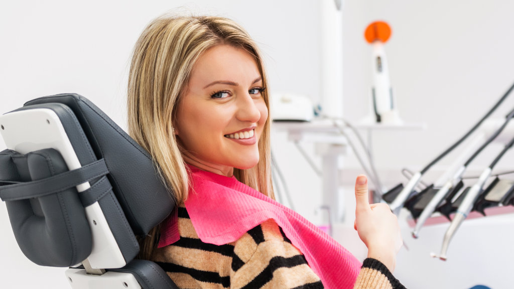 Smiling woman giving a thumbs up in a dental chair before a cleaning