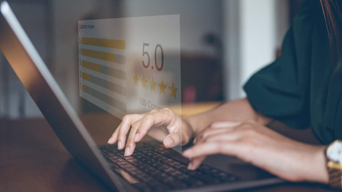 Person typing on a laptop with a 5-star online review overlay