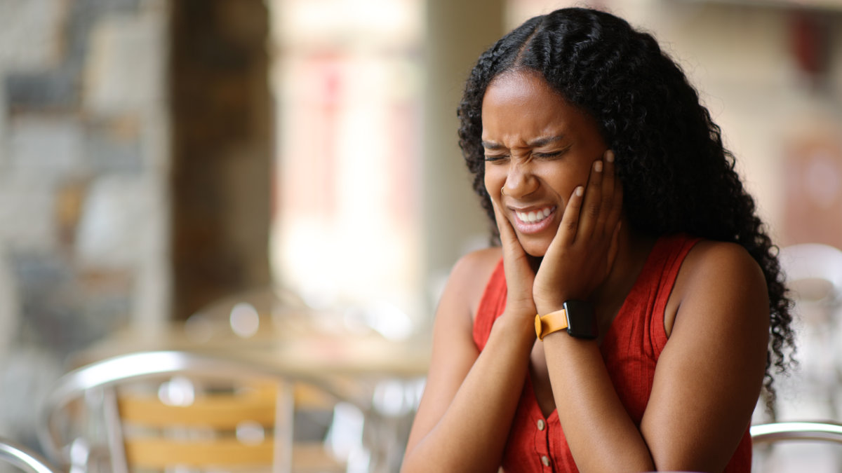 Woman holding her jaw in pain from TMJ discomfort